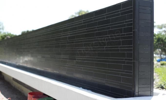 Norstone Ebony Basalt Lynia Interlocking Natural Stone Tiles on a large monument wall under construction for entryway signage at a college in Florida